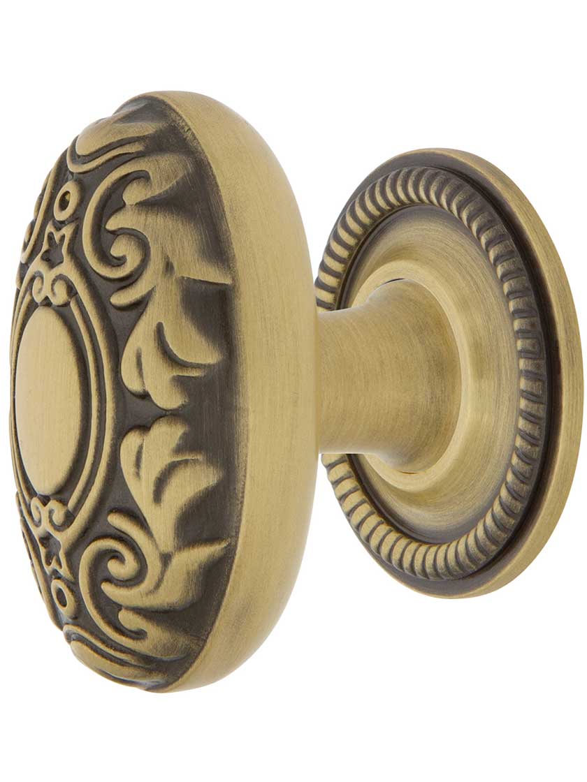 Decorative Oval Cabinet Knob - 1 1/8 inch x 1 3/4 inch with Rope Rosette in Antique Brass.